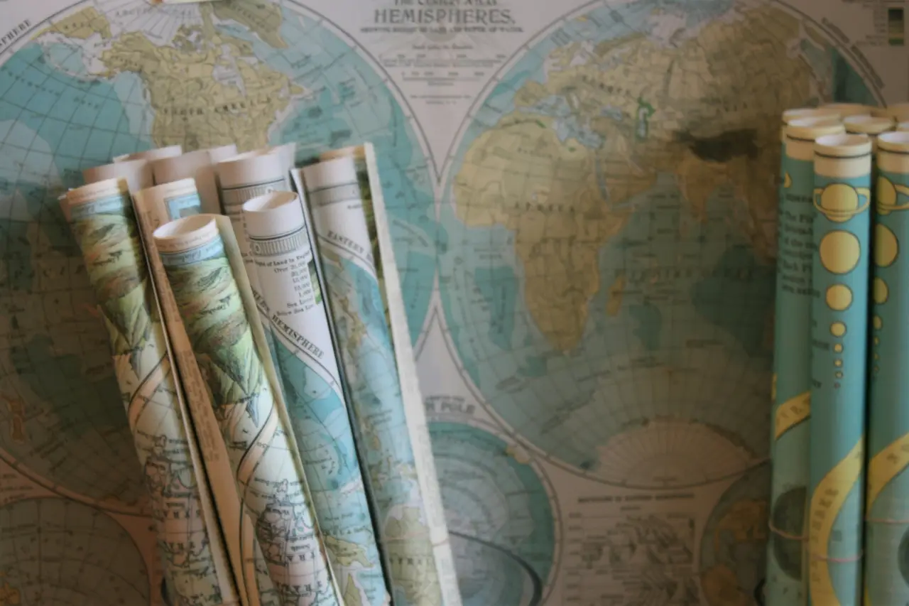 Rolled vintage world maps displayed against an antique globe map background.